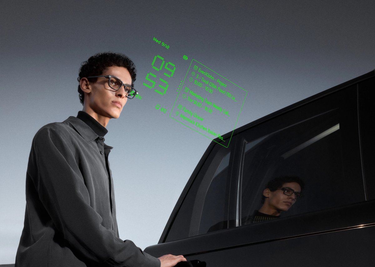 A person wearing Even G2 glasses beside a car, with a promotional green display overlay